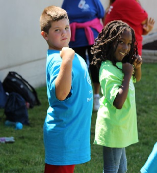 Two children smiling and flexing their arms during an outdoor activity at the Boys & Girls Club of Niagara Falls.
